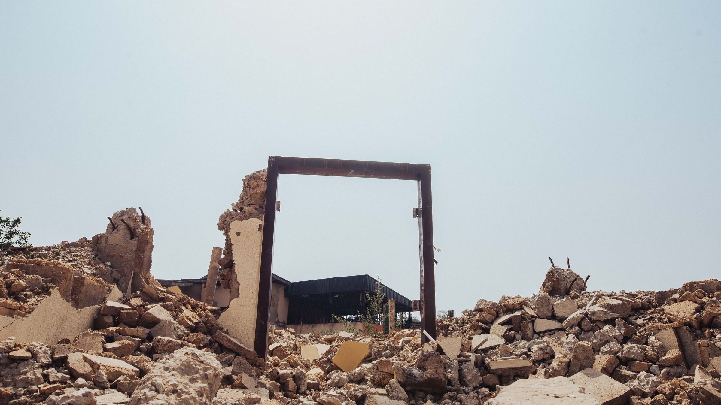Large building part way through demolition with an excavator working the rubble