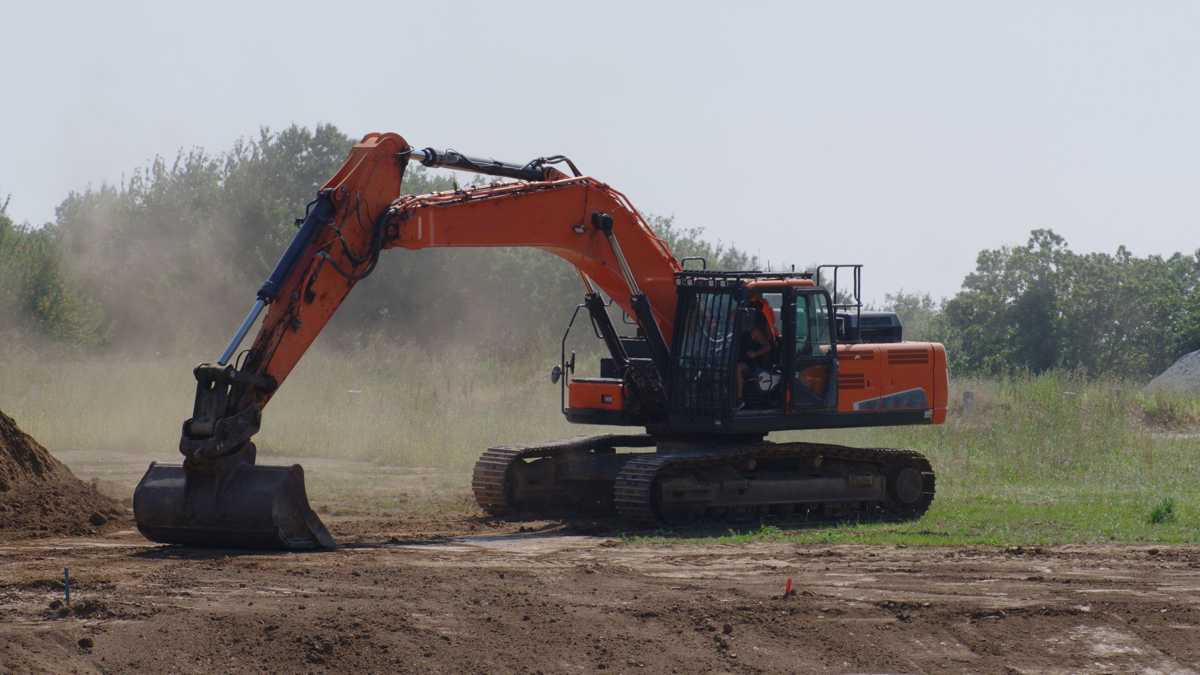 Excavator working a cut, throwing dust