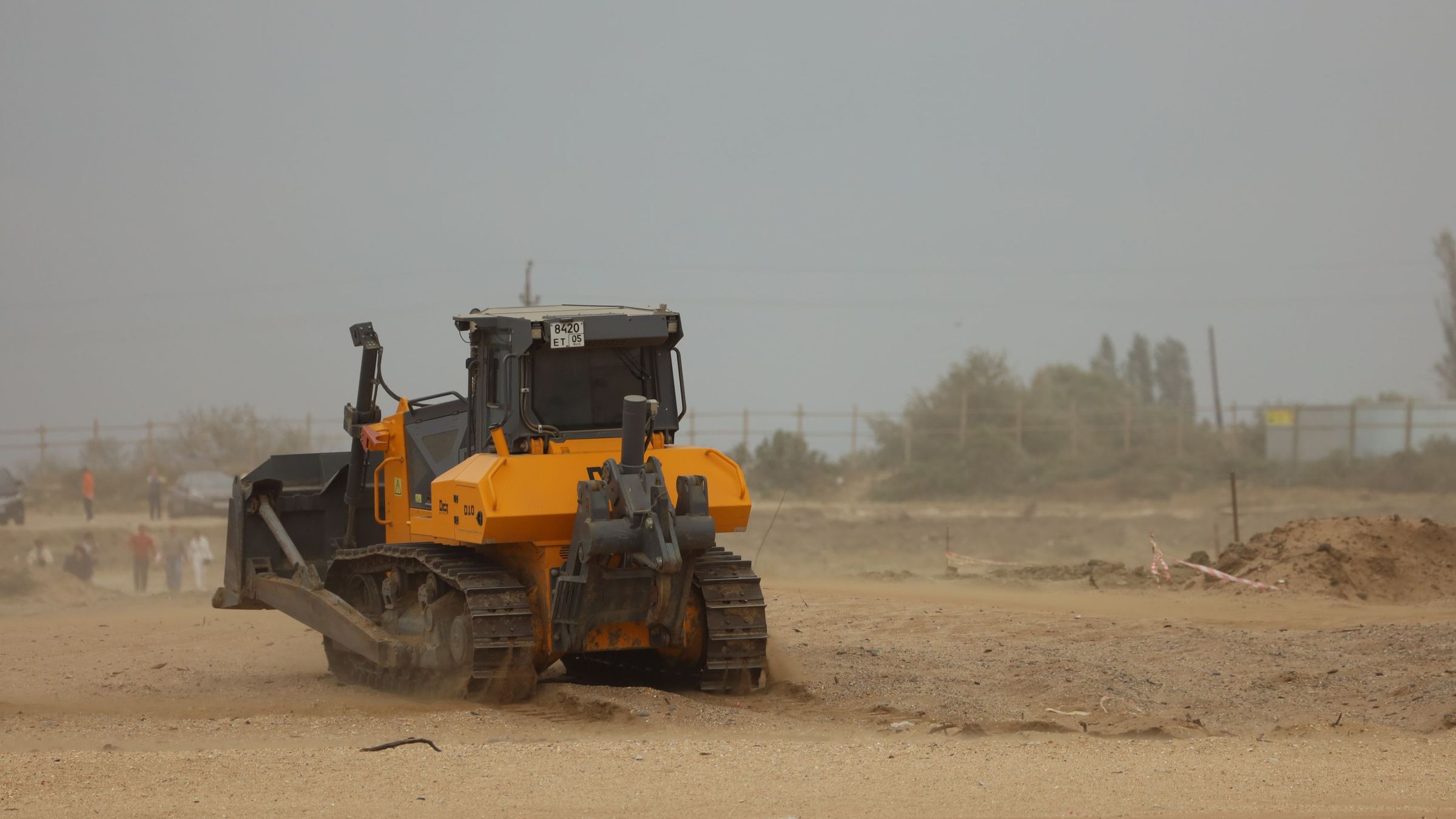 Track dozer pushing material through heavy dust